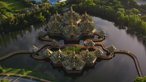 aerial reveal of a green and gold temple on the water ancient city siam, bangkok, thailand