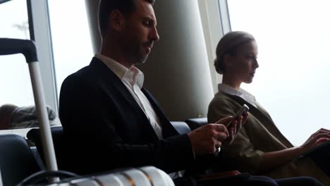 businessman texting on mobile phone while waiting at airport