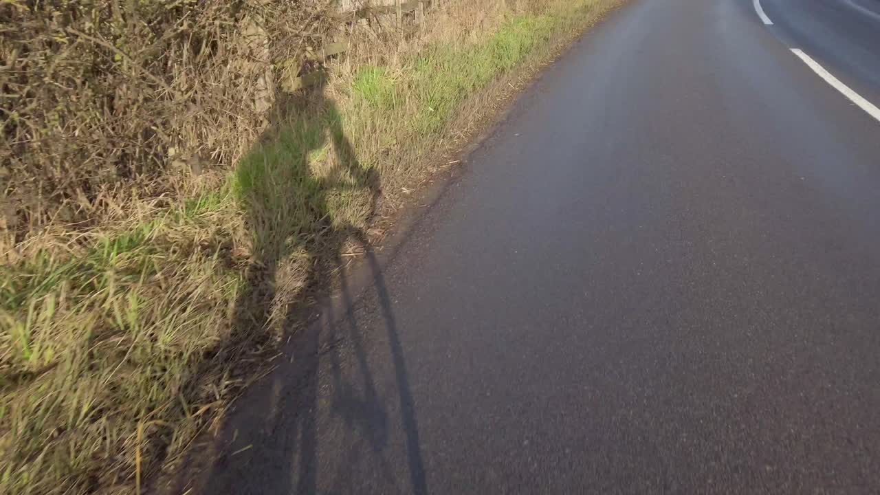 겨울에 자전거 타는 사람의 화창한 시골 차선 그림자에서 pov 샷 도로 자전거 타기 - 화창한 날