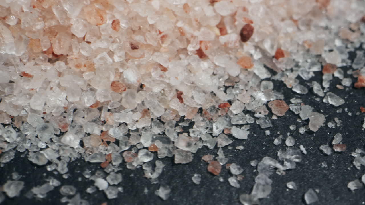 Pink salt close-up macro. Spice for food. Sea salt for bath. Man hand srewing salt on table. High quality 4k footage