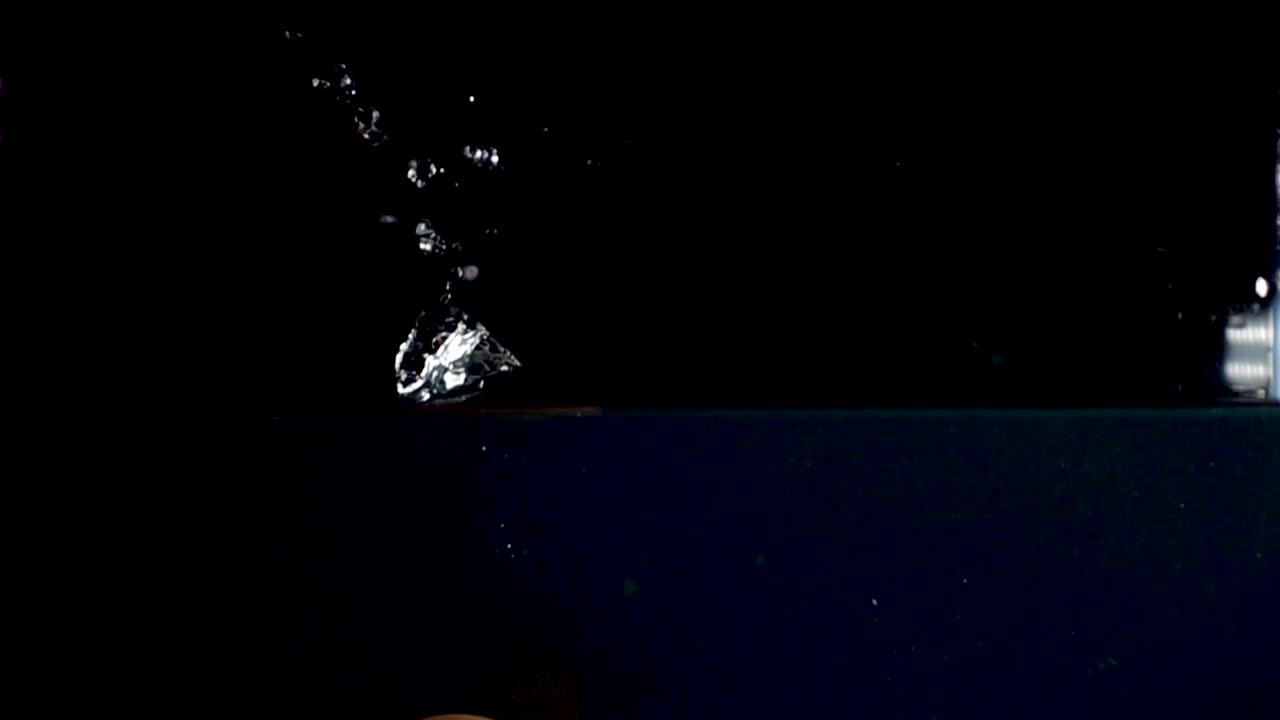 high speed camera slow motion reverse video of an egg splashing into the water. Black background