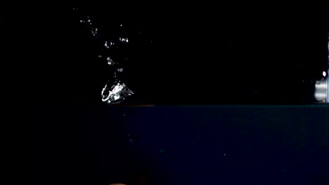 high speed camera slow motion reverse video of an egg splashing into the water. black background