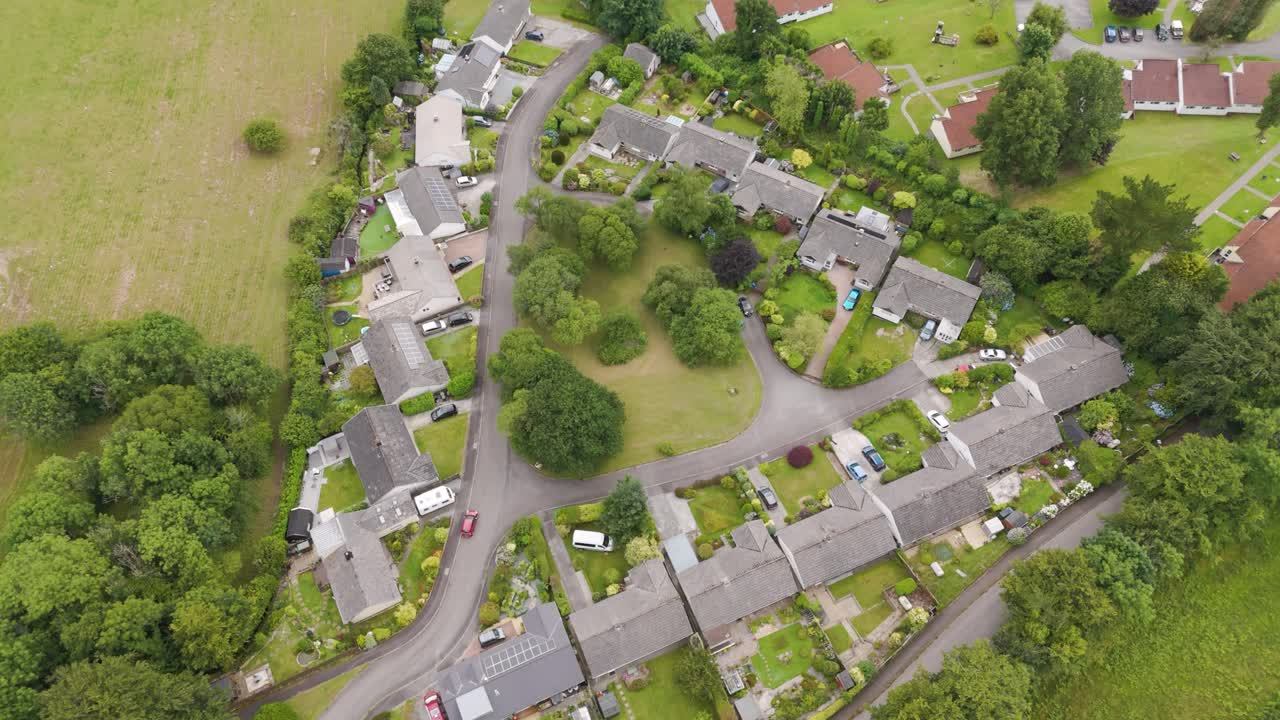Aerial fly-up over a charming hamlet of bungalow homes in England, showcasing the cozy community layout