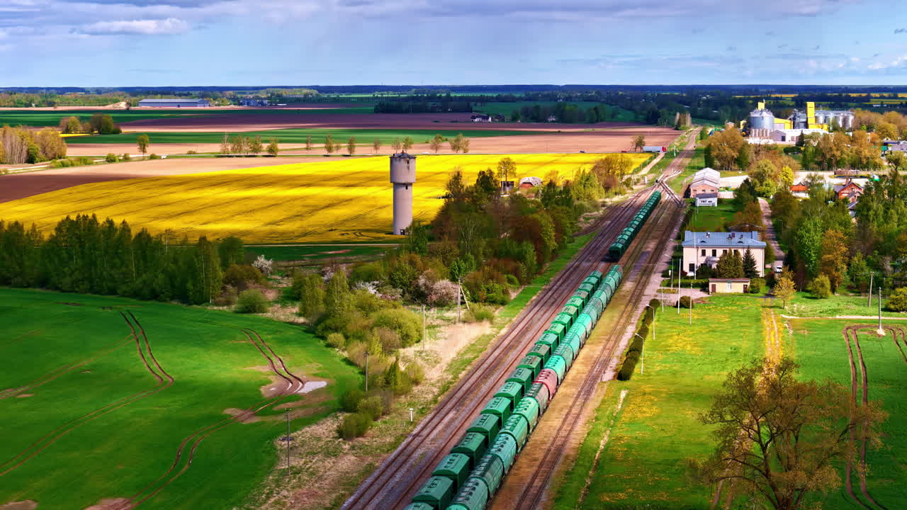 Industrial Trains On Railways Through Rural Landscape With Water Tower. aerial sideways shot