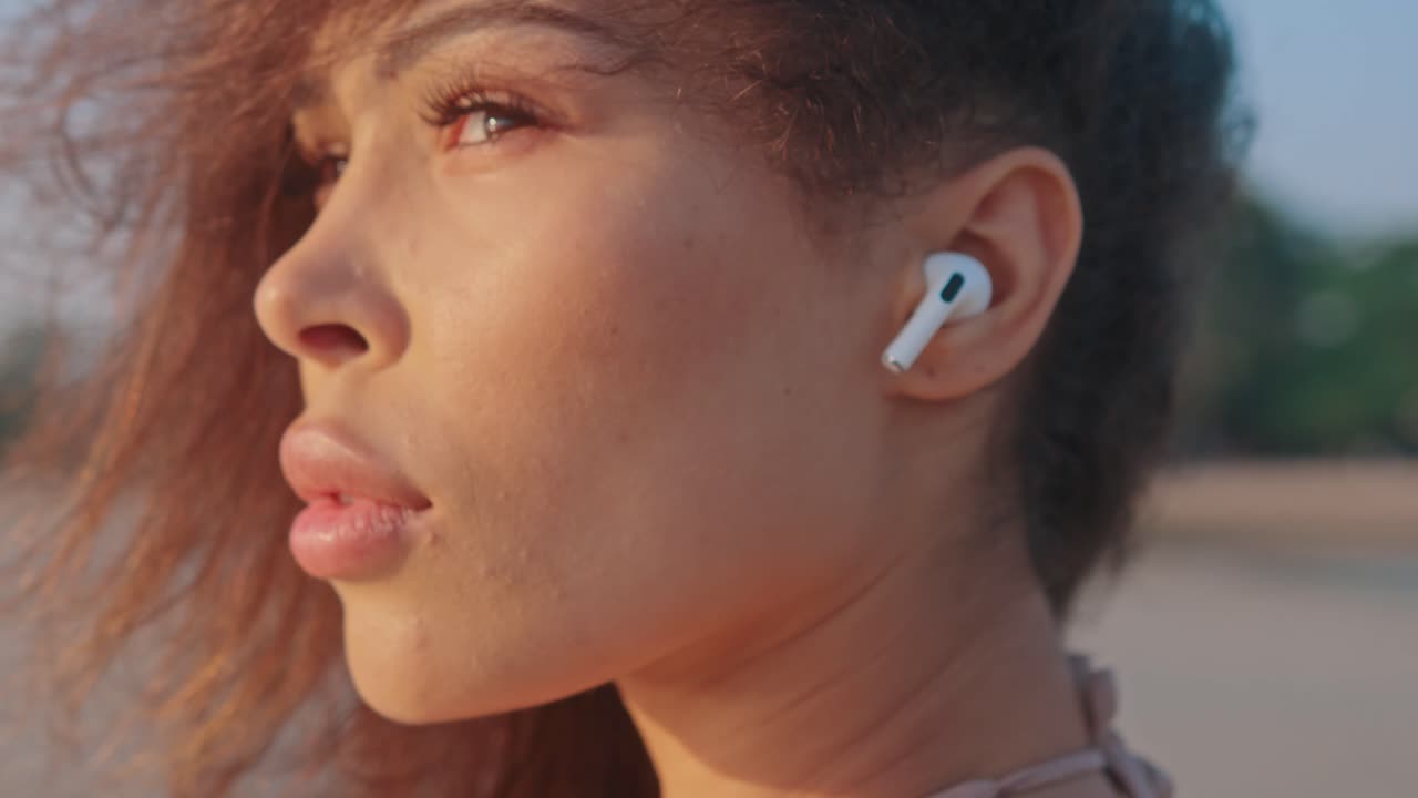 Woman with earbuds at the beach at sunset