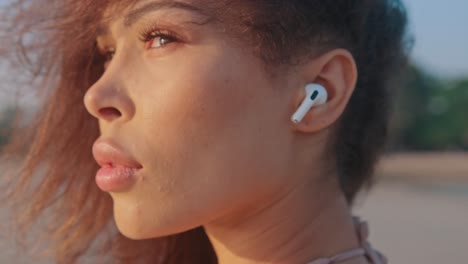 woman with earbuds at the beach at sunset