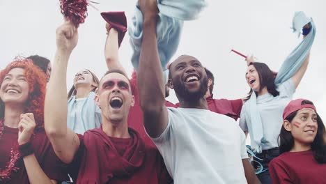 fanáticos del deporte enérgicos apoyando a su equipo en el estadio de fútbol. grupo multirracial de amigos disfrutando de un evento de fútbol deportivo