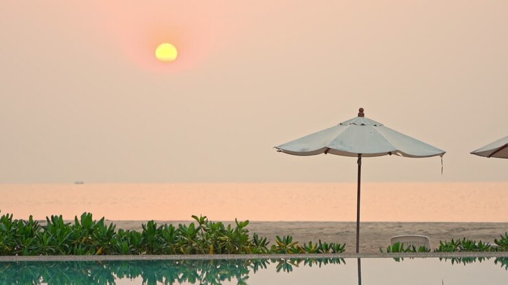 Un sole rosa e giallo che tramonta dietro un ombrellone da spiaggia