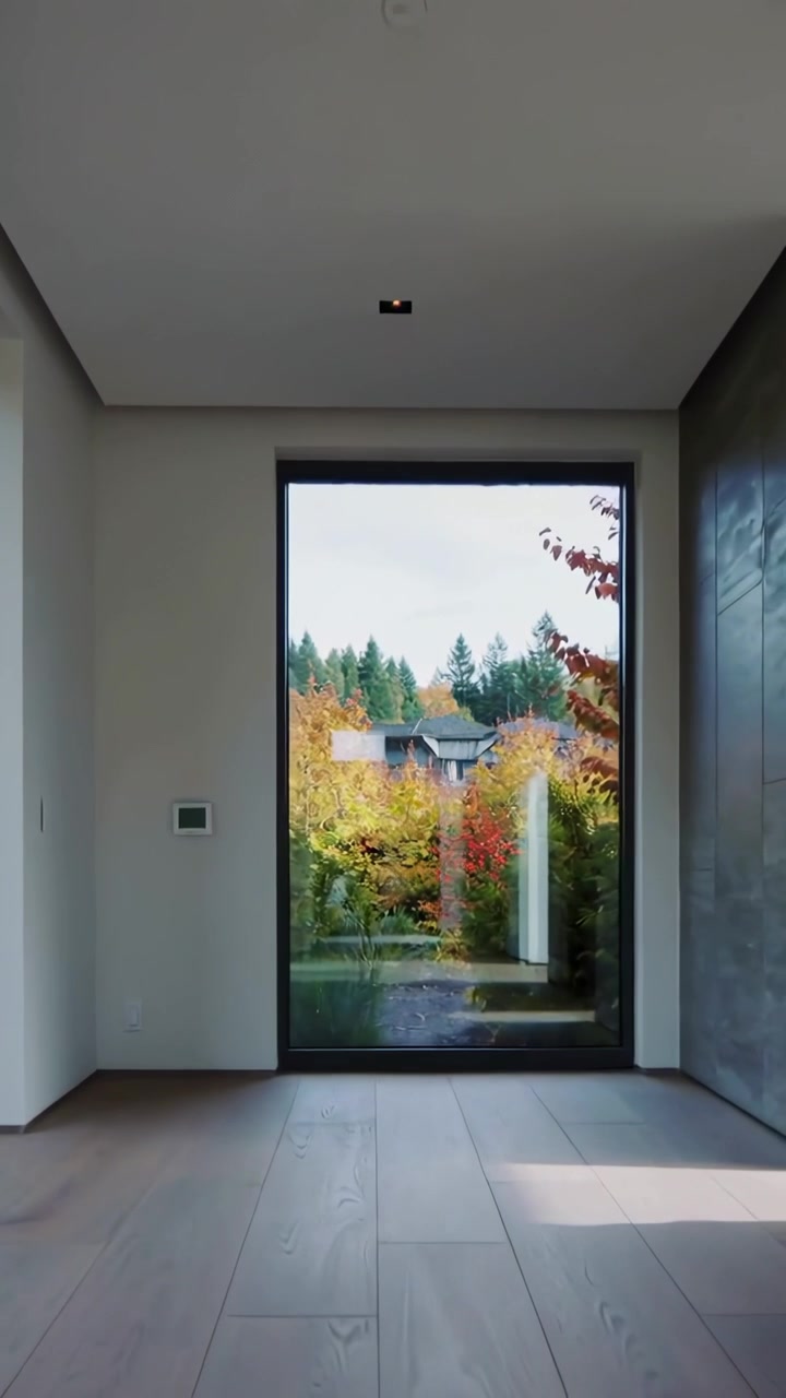 Vertikales Video: Kamera bewegt sich vom Eingang durch das Foyer zu gerahmtem Glasfenster, zeigt Holzboden.