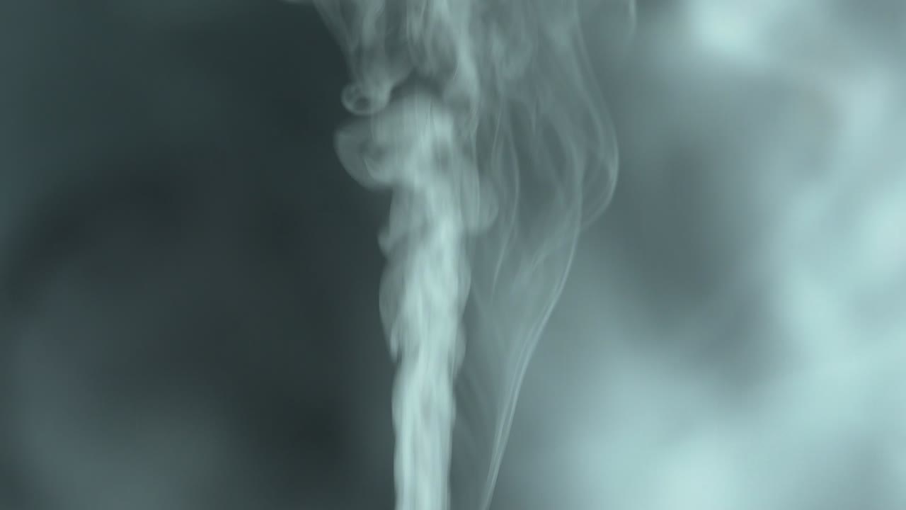 煙は前景で上昇し、薄暗い場所で分離された背景で分散して下に落ちます。