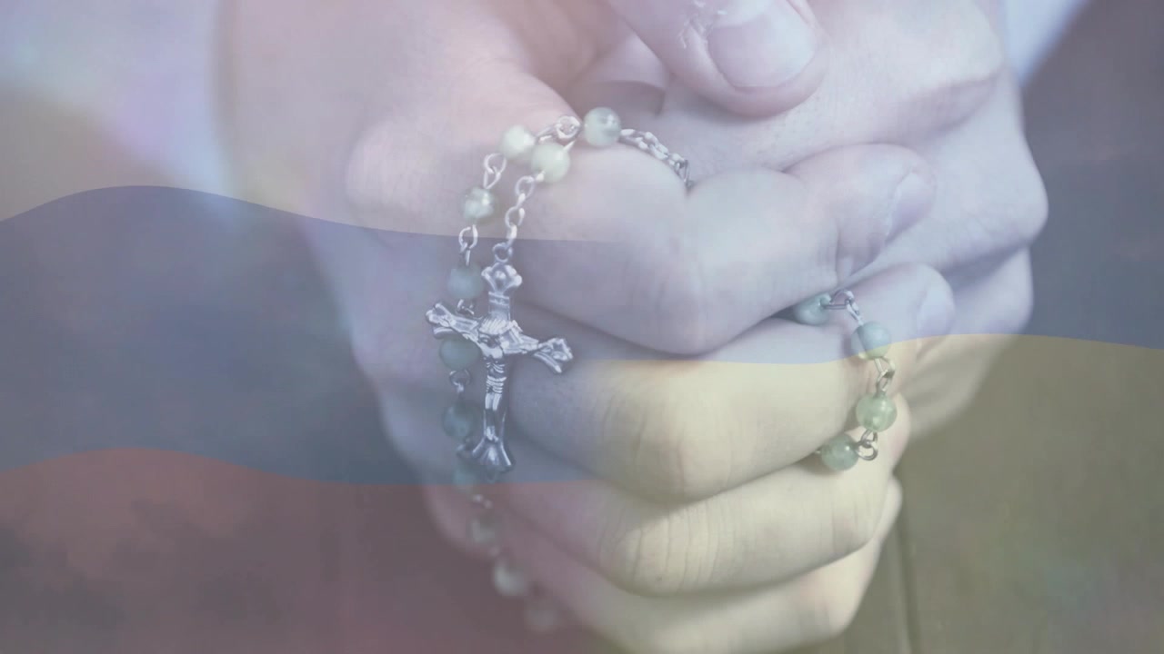 Mãos masculinas segurando um rosário, dedos deslizando as contas, crucifixo girando em oração com faixas duotônicas
