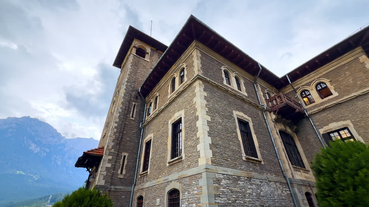 Walking around the beautiful Cantacuzino Castle, Bu?teni, Romania on a rainy day. Low angle view. Hazy mountains at backdrop