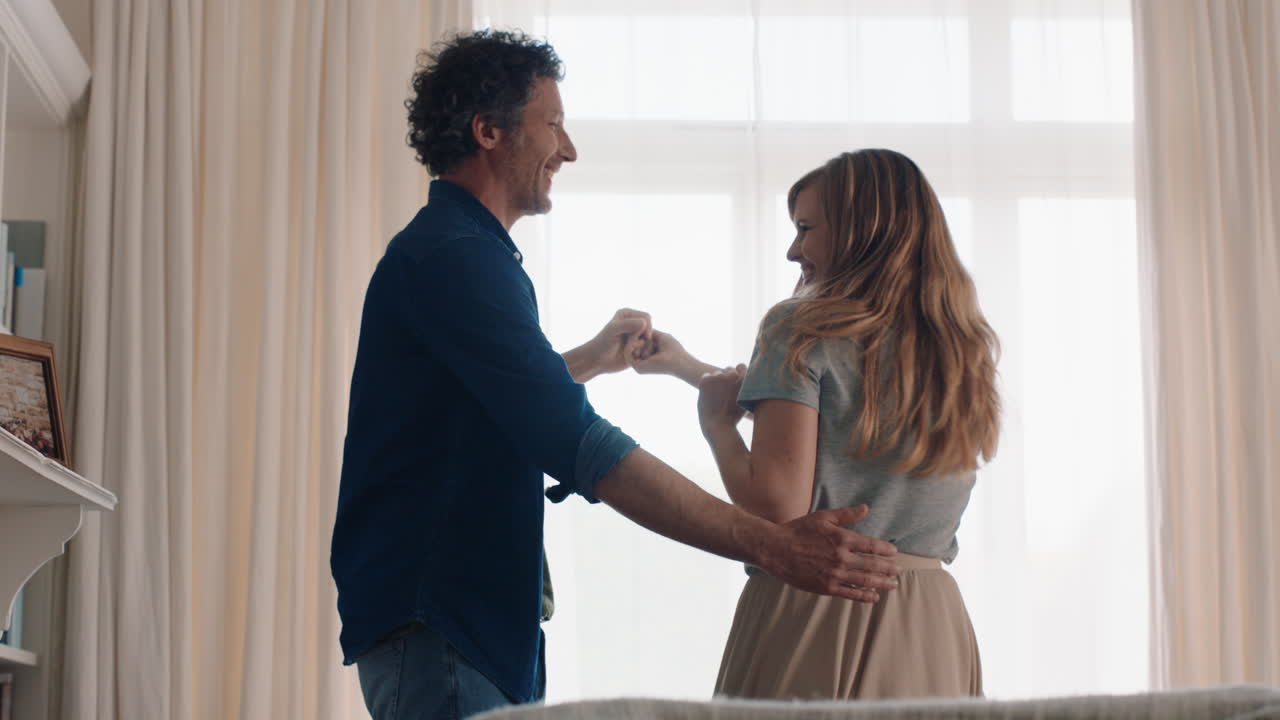 happy young couple dancing together at home celebrating having fun weekend smiling enjoying funny dance in living room successful relationship celebration 4k footage