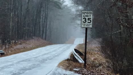 Sanfter-Schneefall-In-Zeitlupe-Auf-Einer-Forststraße-Mit-Einem-Tempolimit-Schild,-Zu-Beginn-Eines-Nordostens-In-Amerika