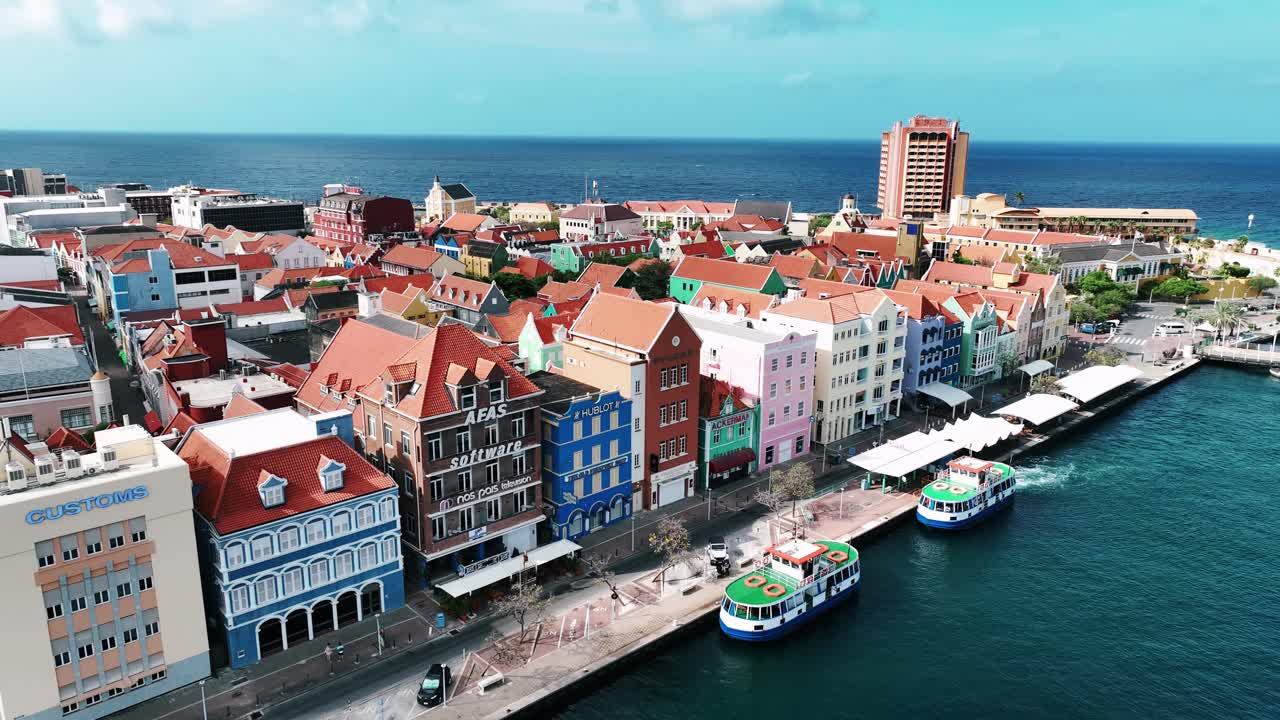 The drone is flying away from the old colorfull houses on the trade quay in Willemstad Curacao Aerial Footage 4K