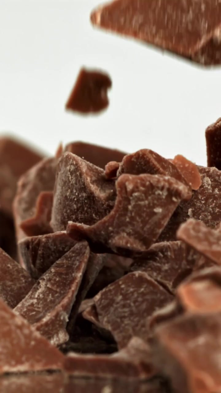 Pezzi di cioccolato che cadono al rallentatore su sfondo bianco