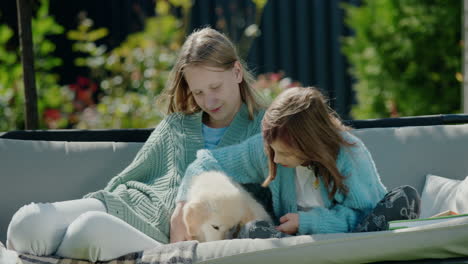 two girls playing with a puppy, sitting on a swing in the backyard of the house