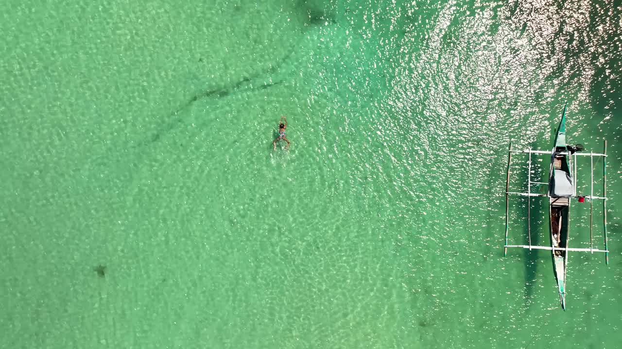 A person swims turquoise waters of Bantayan Philippines Island, Aerial Top Down