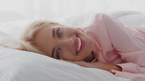 mujer en pijama rosa sonriendo en la cama