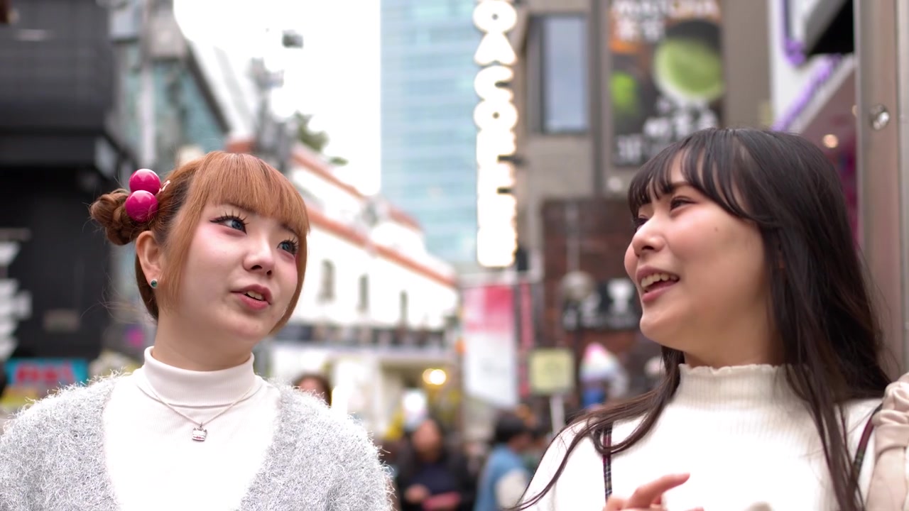 賑やかな原宿竹下通りを歩きながら、話したり笑ったりするおしゃれな日本の若い女性2人。