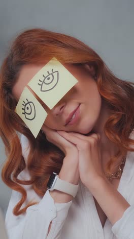 young caucasian woman secretary with funny paper stickers hiding closed eyes