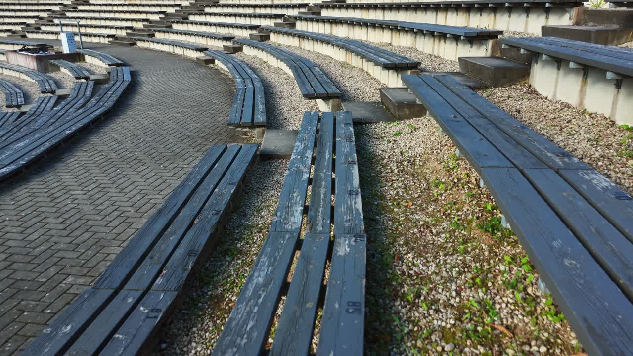 Empty wooden benches curving through Sauleskalns open air amphitheater in Talsi, Latvia, sitting quietly beneath overcast skies, evoking peaceful anticipation