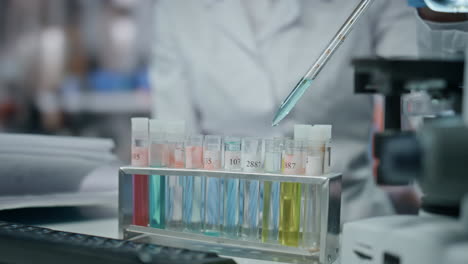 mano del científico usando pipeta llenando el tubo de ensayo realizando un experimento de cerca.