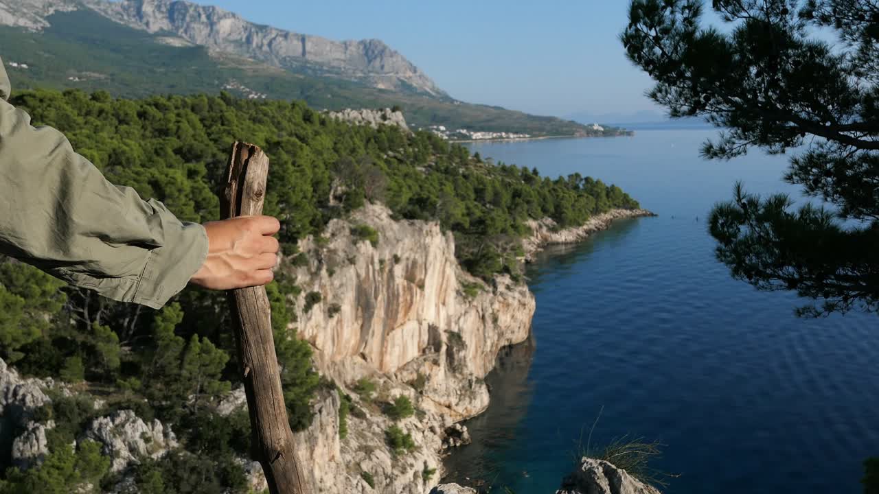 viajero excursionista con bastón de caminar mirando la impresionante vista del mar de la montaña en la caminata