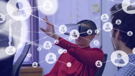 Animation-of-network-of-connections-with-icons-over-diverse-business-people-using-vr-headset