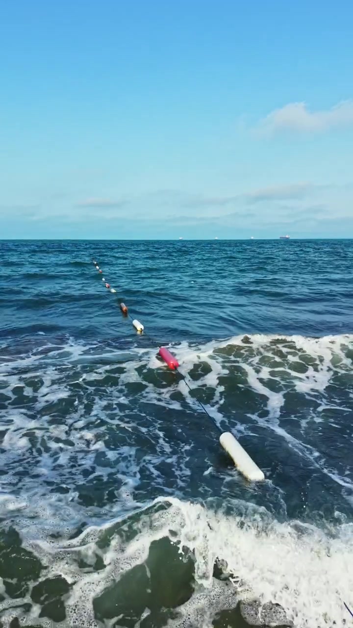 Fiskenet er sat ud langs kystlinjen, med bølger der rammer kysten om dagen på en strand nær havet