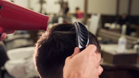 peluquero seca secador de pelo en barbería