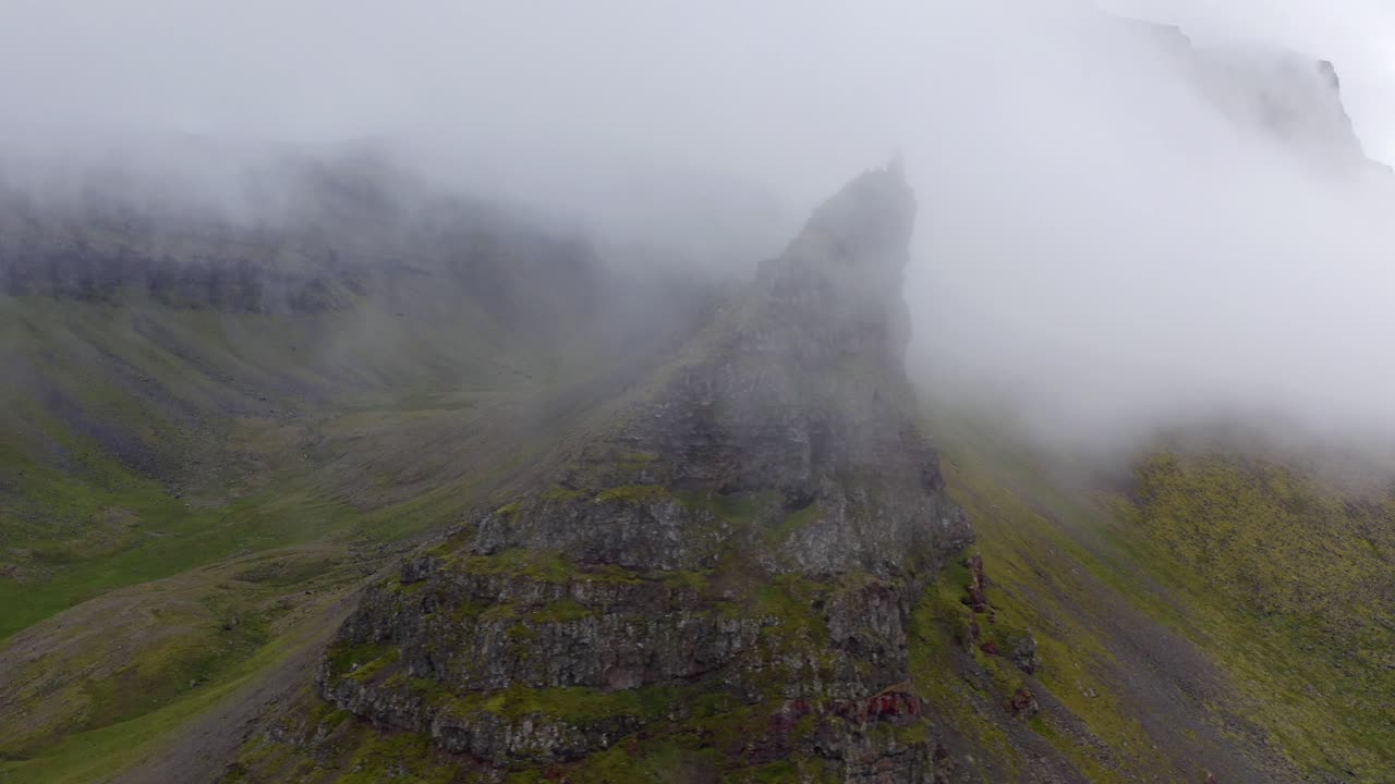 imágenes vívidas de nubes reunidas alrededor del pico de montañas rocosas verdes en una mañana brumosa en islandia