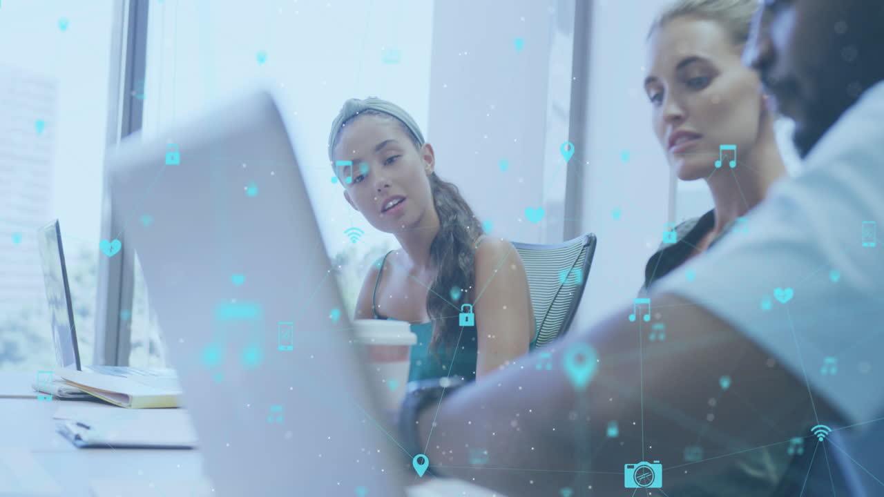 Animation of network of digital icons against diverse colleagues discussing over a laptop at office