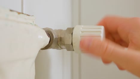 man opening and closing a radiator valve in a bathroom