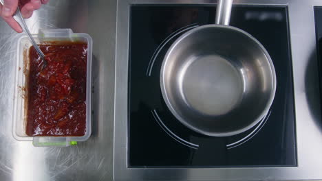 chef puts sauce with tomatoes and pepper in pan