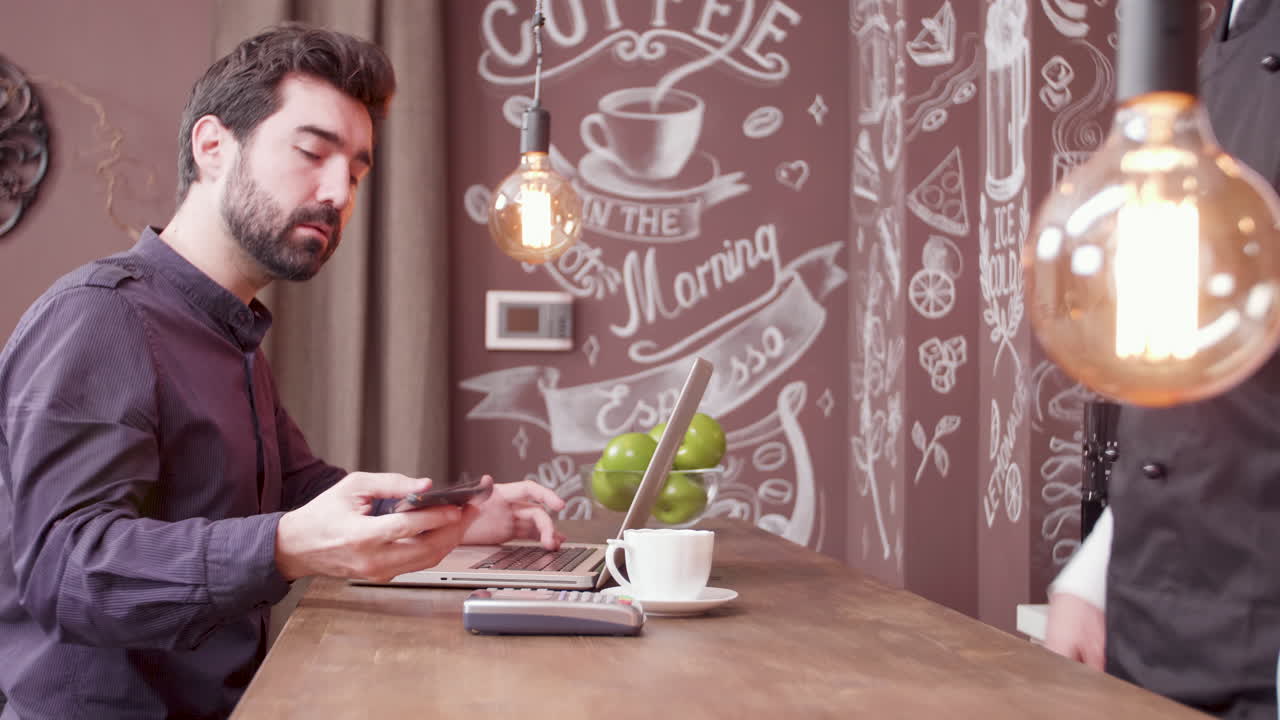 Uomo che lavora in un bar con laptop e smartphone