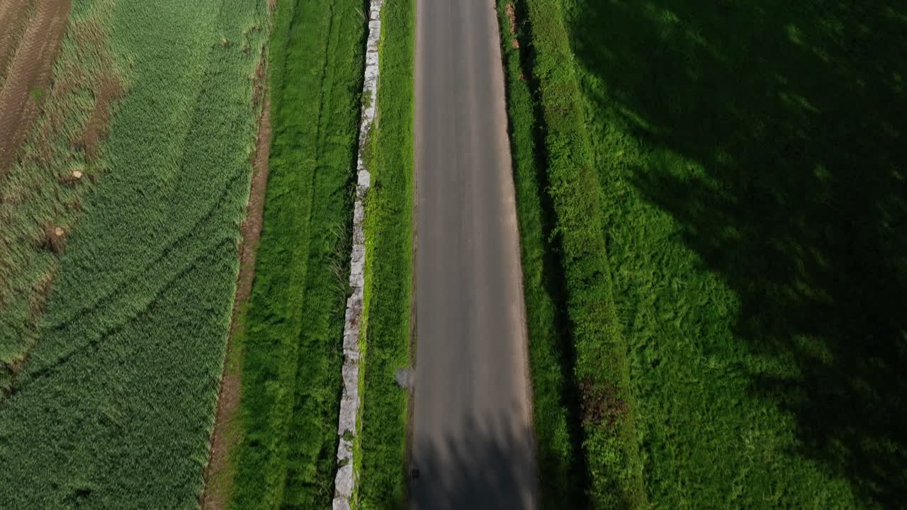 Caledon Border Wall, County Tyrone, Northern Ireland, May 2023. Drone moving forward above stone heritage, clean road symmetry, lush green fields and rural textures.