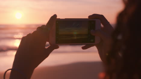 close up young woman on beach using smartphone taking photo of beautiful sunset enjoying sharing summer vacation travel experience on social meda