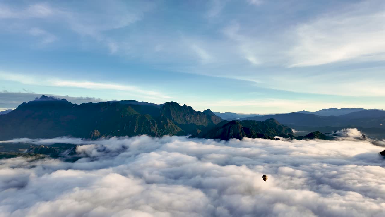 Hot air balloon floating over a sea of clouds and karst mountains in Laos during morning