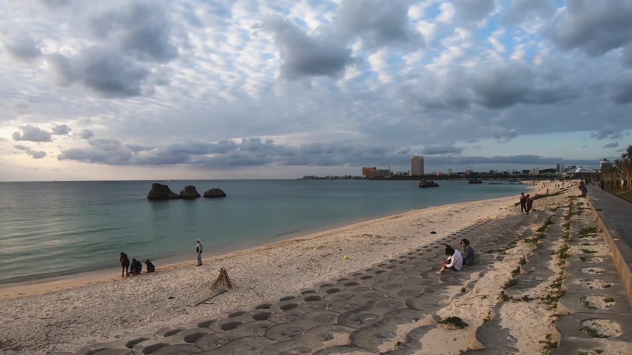 Time lapse of people enjoying the evening as clouds fly overhead. Araha Beach, Okinawa, Japan
