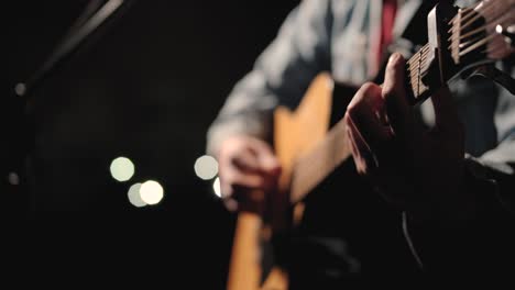 a musician is playing guitar on a large stage with audience members holding flashlights in the background. the auditorium is filled with beautiful flashing lights.