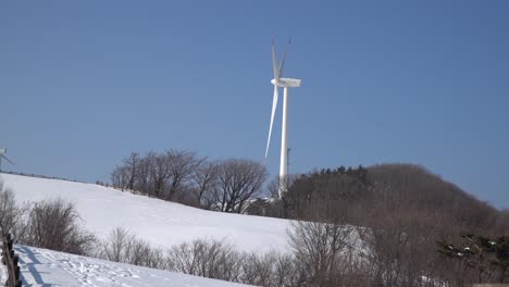 single windmill is moving to generate electricity, it is seen in the snow-covered mountain, south korea