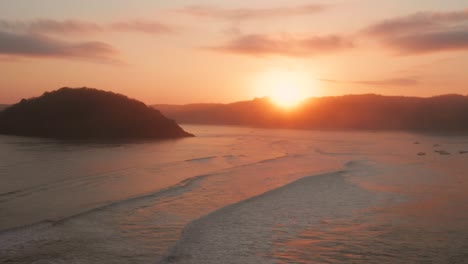 Sunrise-at-the-surf-spots-of-Gerupuk-in-Lombok,-with-a-view-on-the-bay-with-the-fishing-boats-and-surfers