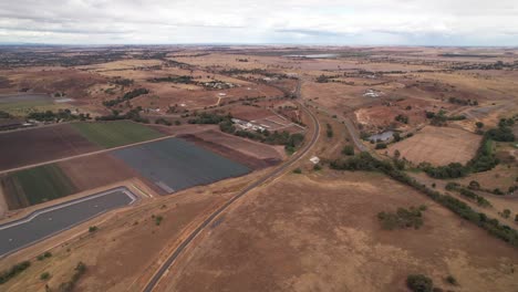 Colourful-farmland-panning-to-black-coal-mine-aerial,-rural-Australia