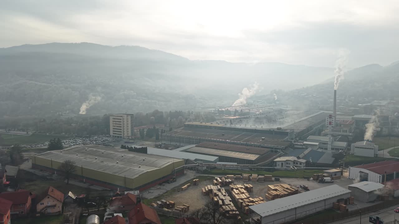 Drone mostrando fumaça tóxica saindo de uma fábrica, poluição do ar em uma pequena cidade industrial