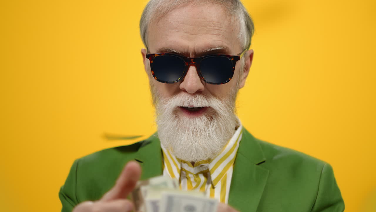 un anciano satisfecho viviendo bajo la lluvia de dinero, un tipo maduro contando dólares en el interior.