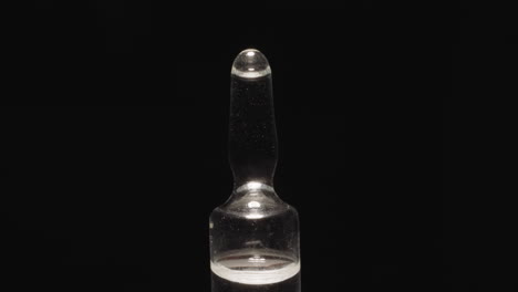 sealed glass ampoule with long tip on black background