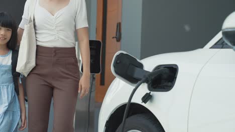 progressive lifestyle of mother and daughter with ev car and charging station.