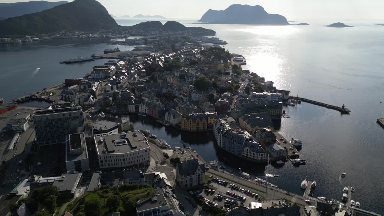 4K drone footage panning slowly sideways above Ålesund city center, Norway, focusing on the colorful Art Nouveau waterfront buildings and harbor under bright summer sunlight