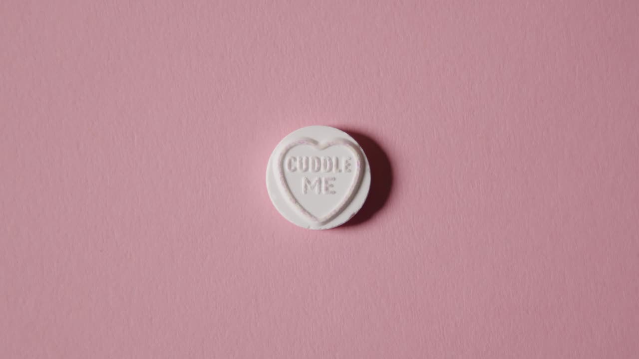 분홍색 배경에 나를 껴안아라 메시지와 함께 심장 사탕을 손에 들고